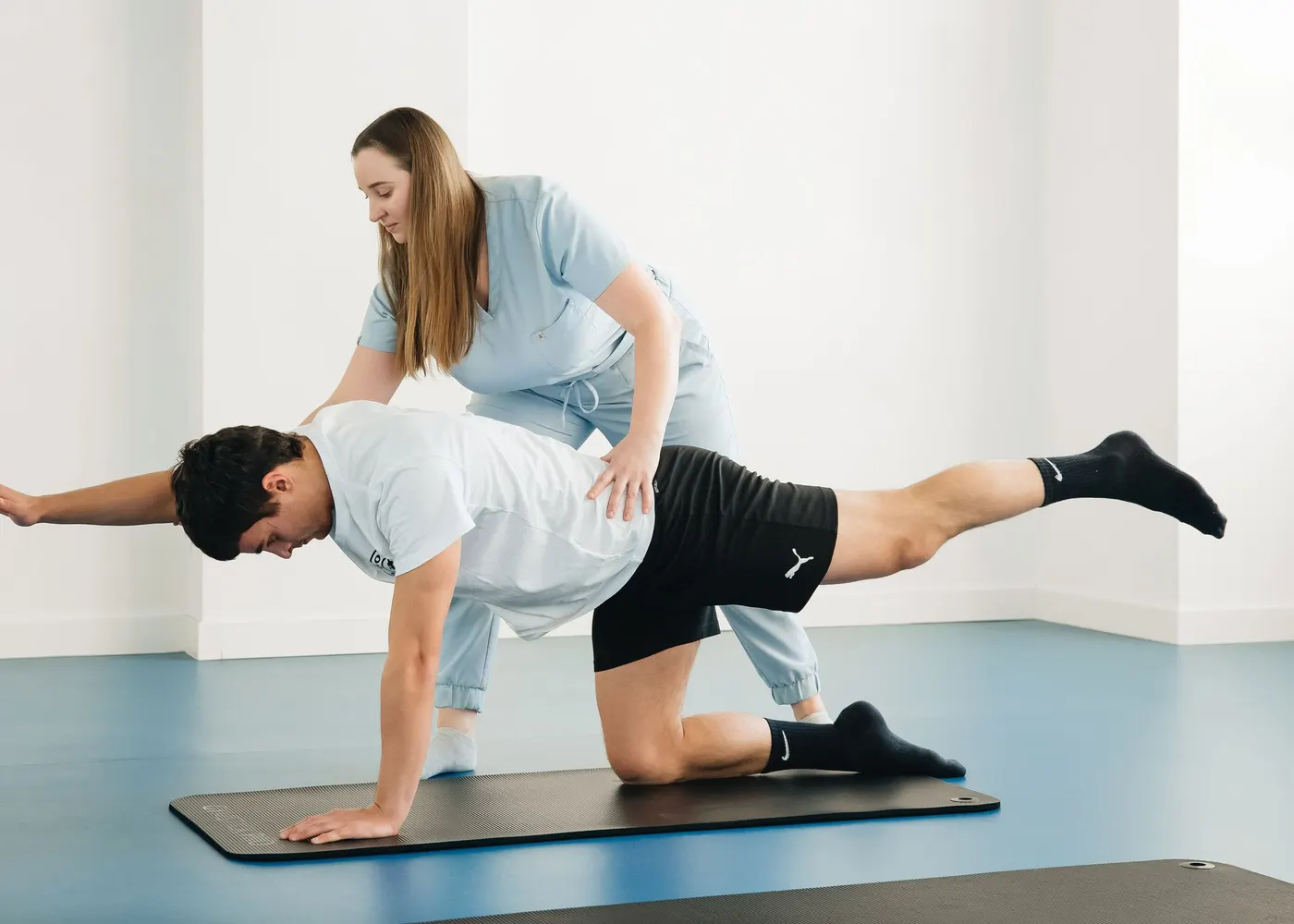 Fisioterapeuta corrige a postura de um paciente durante exercício guiado no tapete